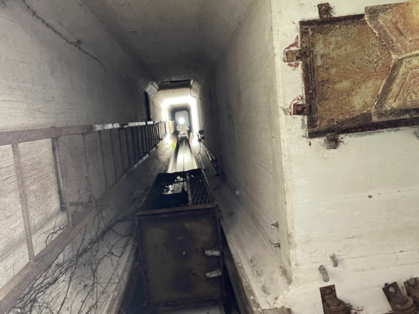 A long concrete passage inside the dryer with a ladder along one side, before restoration